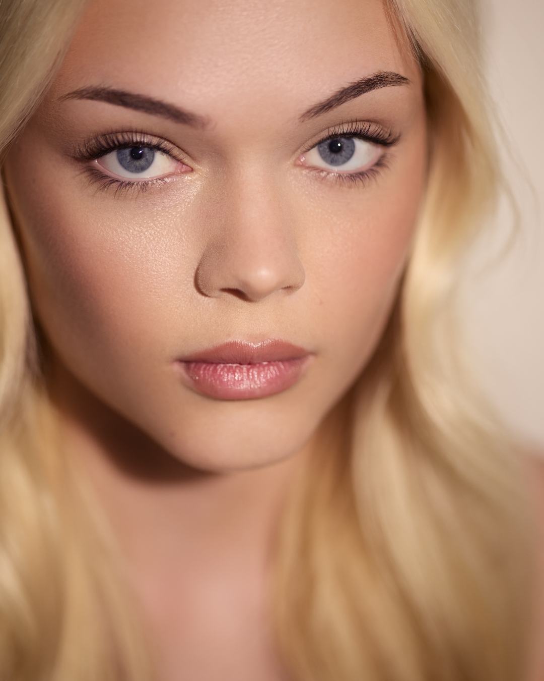 A close-up portrait of a blonde woman with blue eyes, wearing subtle makeup and looking directly at the camera showing Brik & Pearl Lash Lift Results